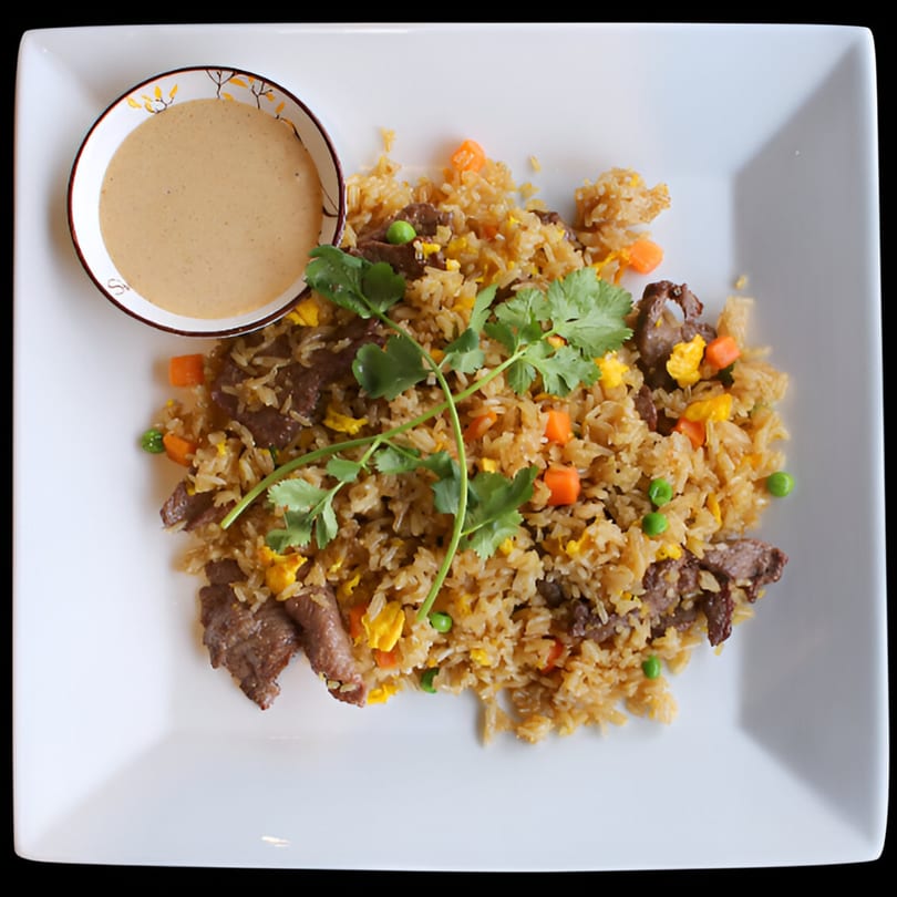 Evie's Vietnamese Kitchen's beef fried rice with vegetables and cilantro, served with a side of sauce.